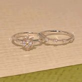 Snow-blossom halo engagement ring and matching contour band in solid gold on wood surface